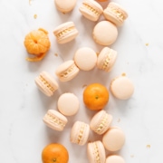 Mandarin orange macarons scattered on marble counter