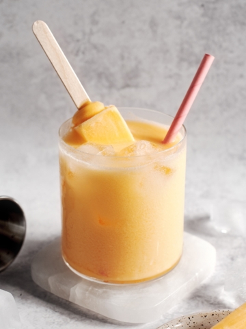 Mango melona soju cocktail with melona popsicle sticking out