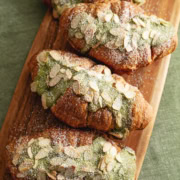 Matcha almond croissants lined up on a wooden serving board.