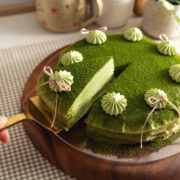 A slice of matcha crepe cake being slightly lifted from the rest of the cake.