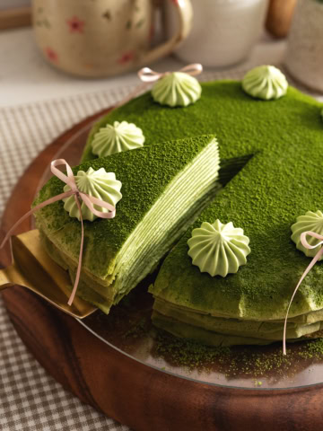 A slice of matcha crepe cake being slightly lifted from the rest of the cake.