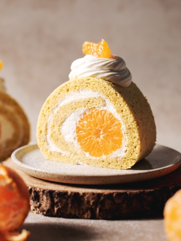 slice of orange swiss roll with mandarin orange in the middle