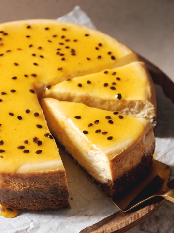 A slice of passionfruit cheesecake on a gold cake server.