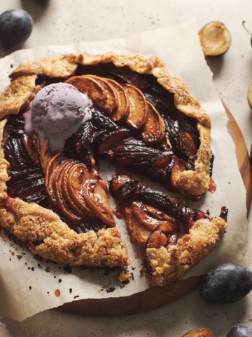 Glossy peach plum galette with a scoop of melting ice cream.