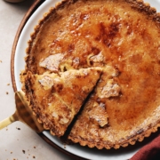 Pie server lifting a slice of pumpkin crème brûlée tart from the plate