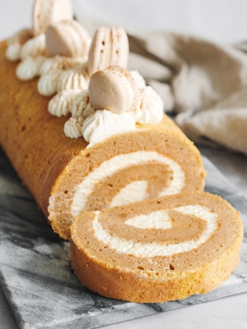 Pumpkin swiss roll with sliced piece laying in front of it