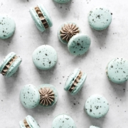 Blue macarons showing oreo filling inside scattered on gray background