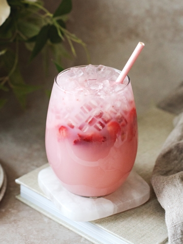 Glass of pink strawberry soju cocktail on a book
