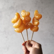 Hand holding skewers of tangerine tanghulu
