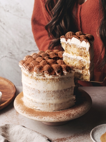 Lifting a slice of tiramisu layer cake with serving knife