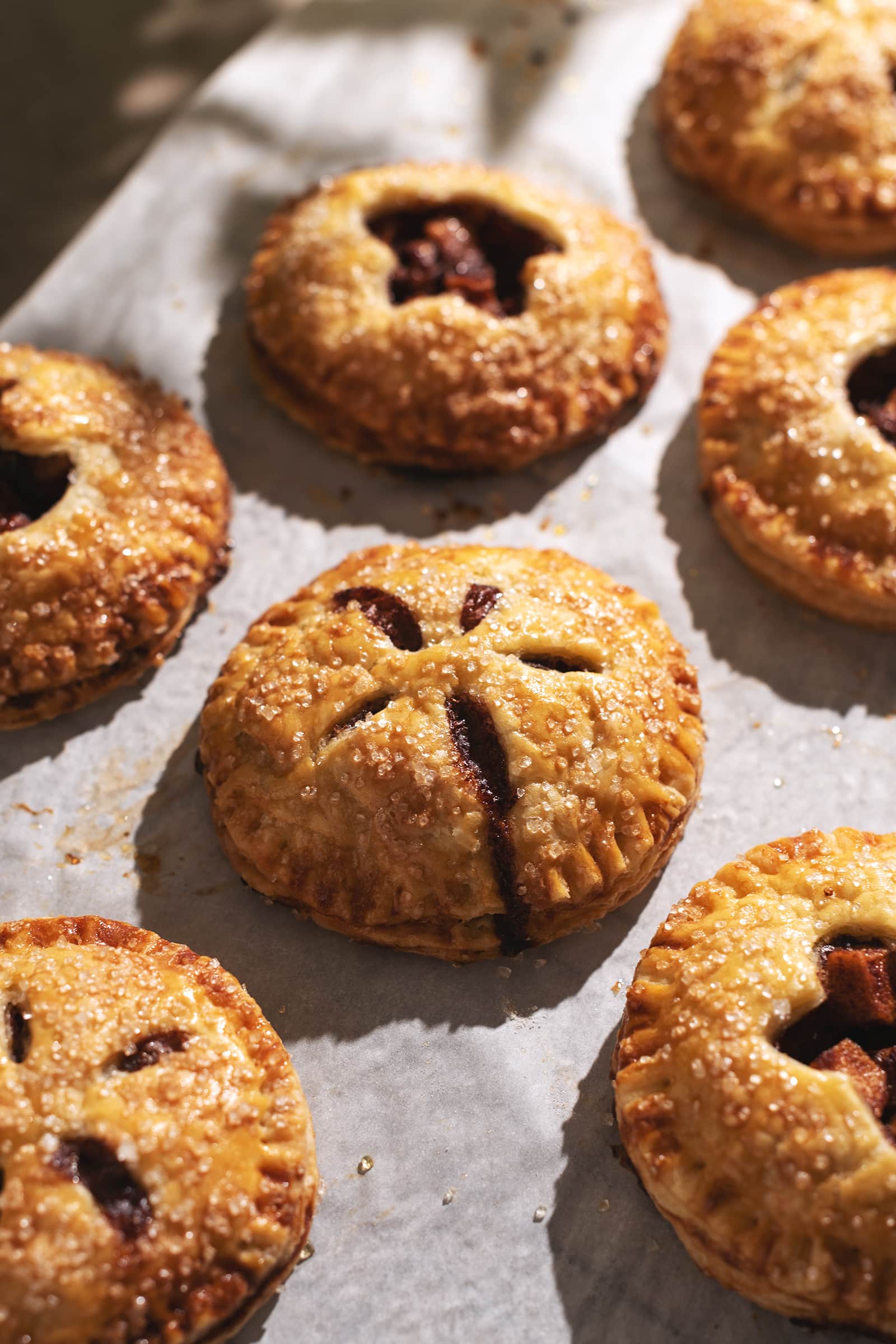 Mini apple pie with filling dripping out of it.