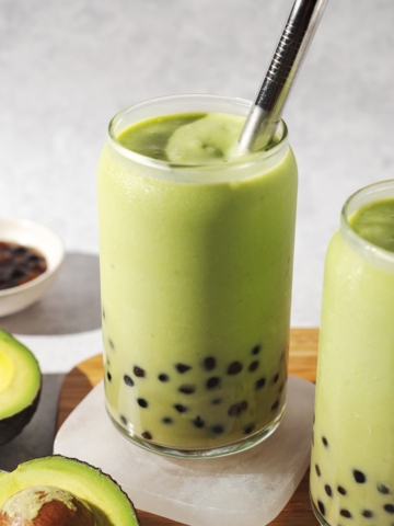 Glass of avocado boba with metal straw.