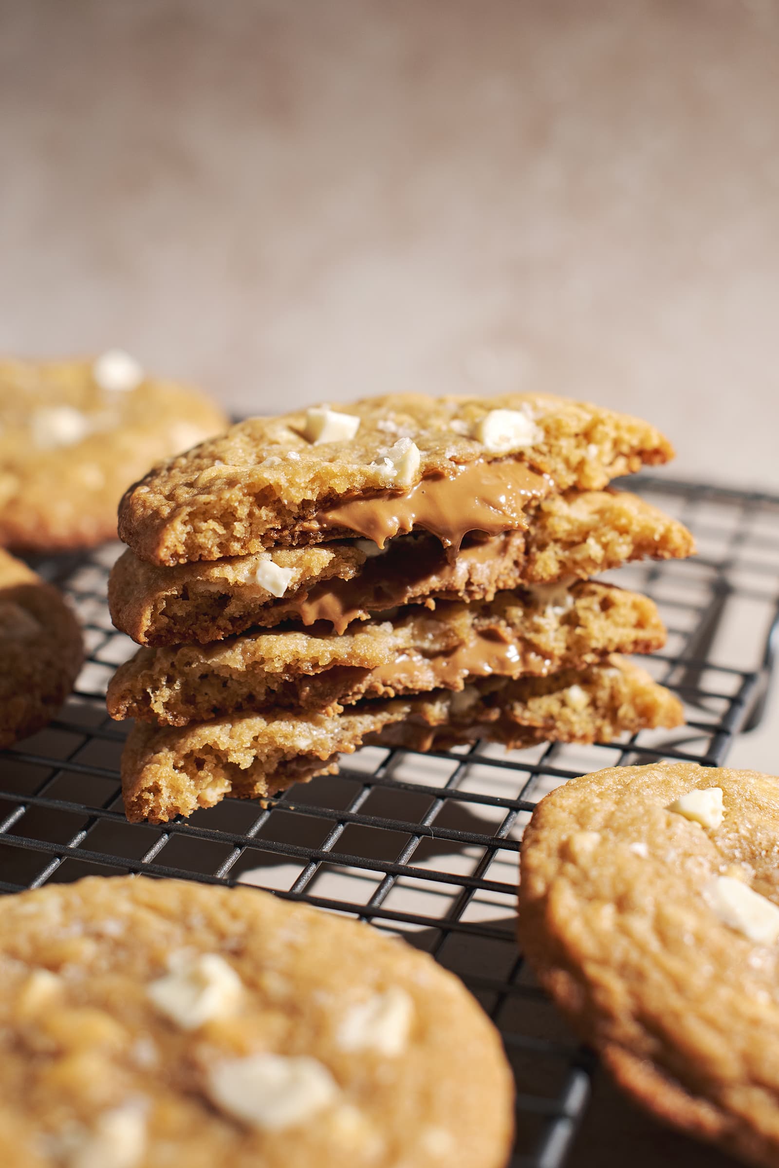 Stack of white chocolate chunk cookies broken in half to show biscoff filling int he middle.