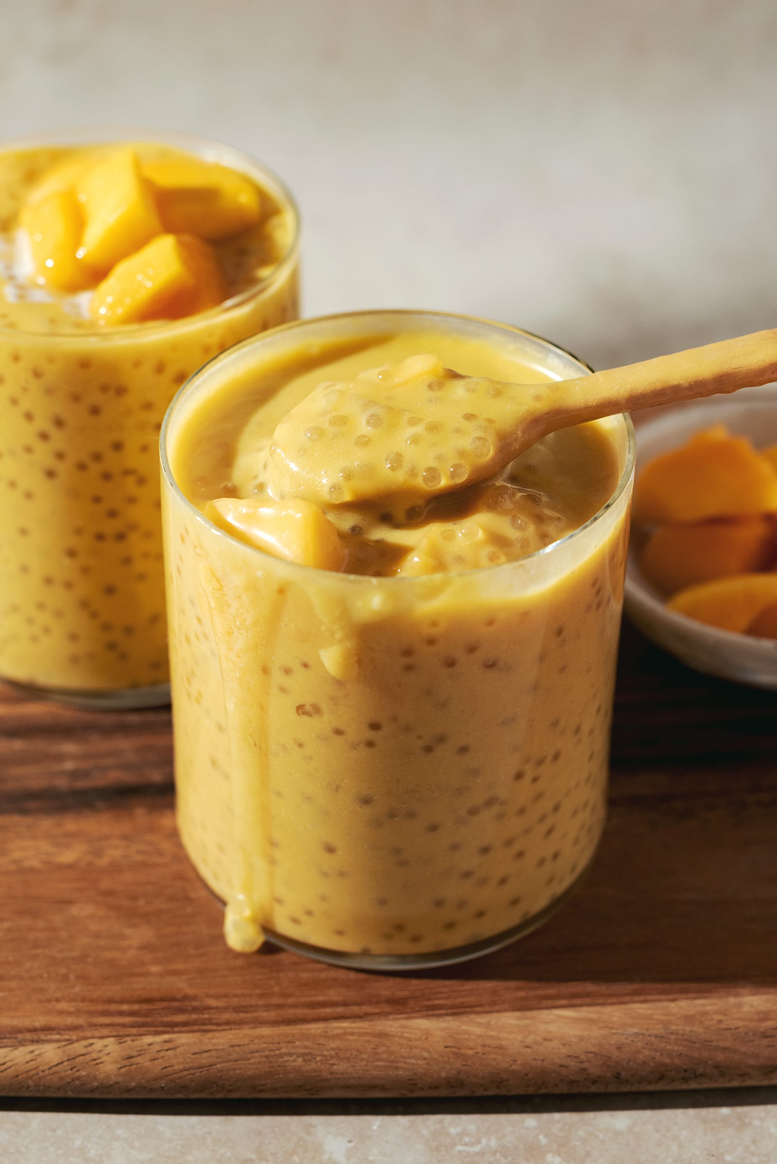 Mango sago being scooped up from a cup with a spoon.