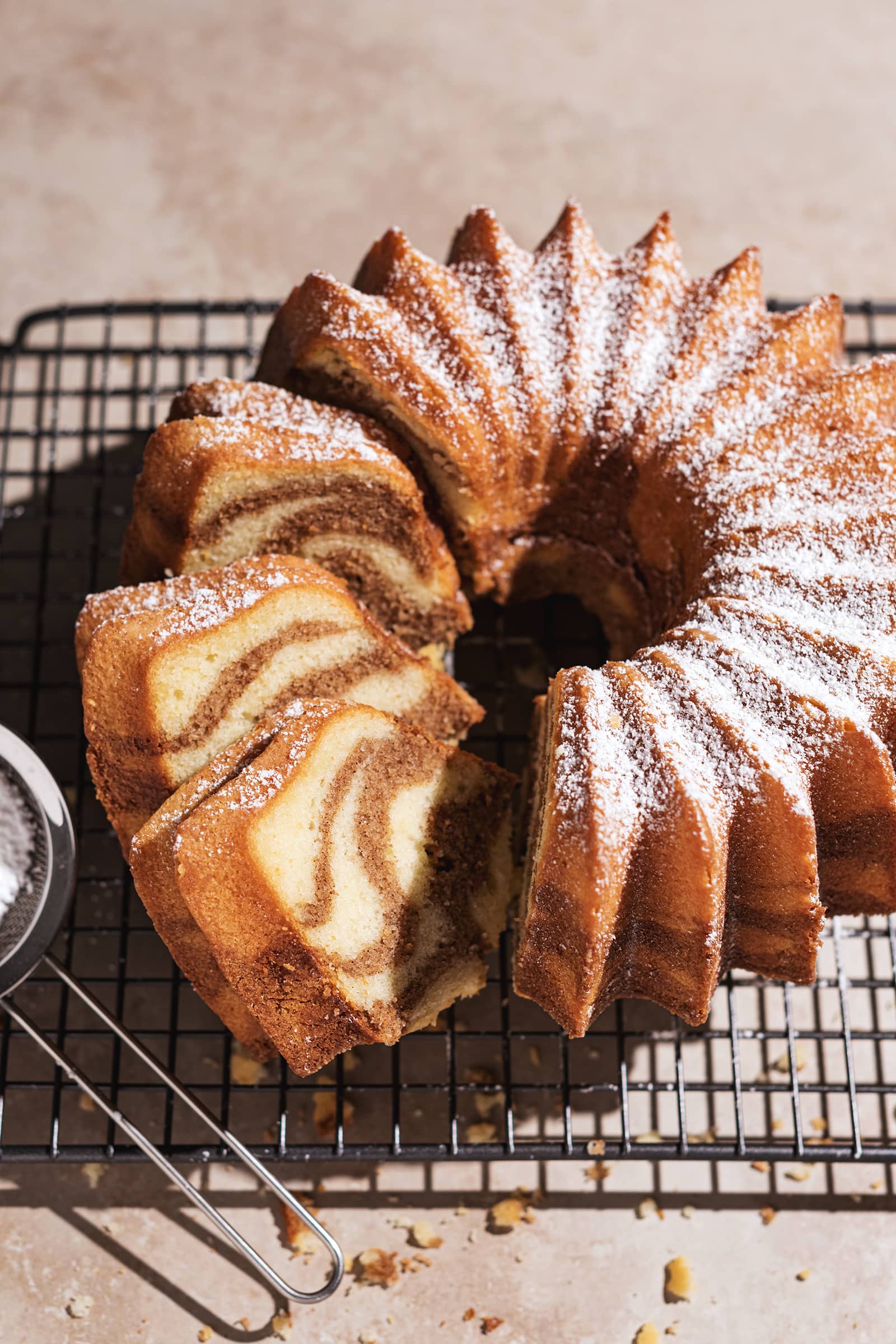 Cinnamon swirl bundt cake on wire rack with three slices cut from one side.