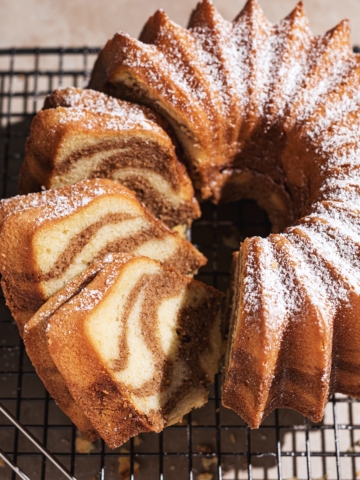 Cinnamon swirl bundt cake on wire rack with three slices cut from one side.
