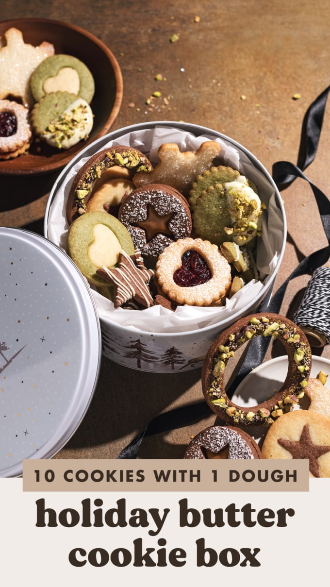 Assorted butter cookies in a round tin with cookies scattered around it.