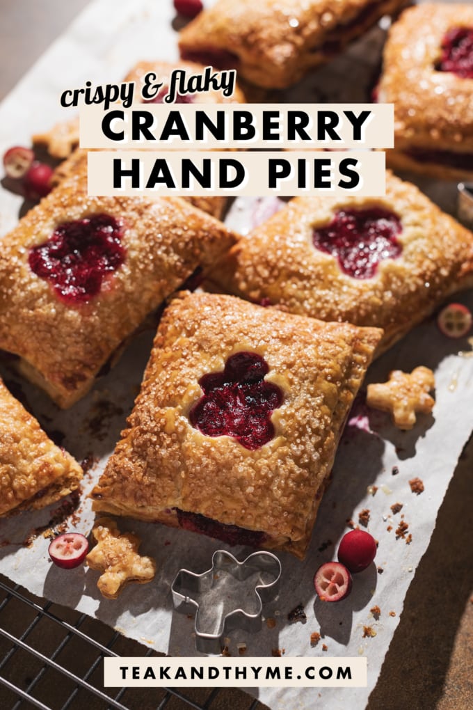 Cranberry hand pies with cutouts scattered on parchment paper.