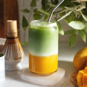 Glass filled with a layer of mango puree on the bottom and matcha on top.