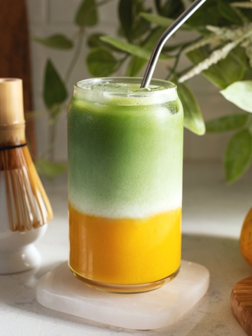 Glass filled with a layer of mango puree on the bottom and matcha on top.