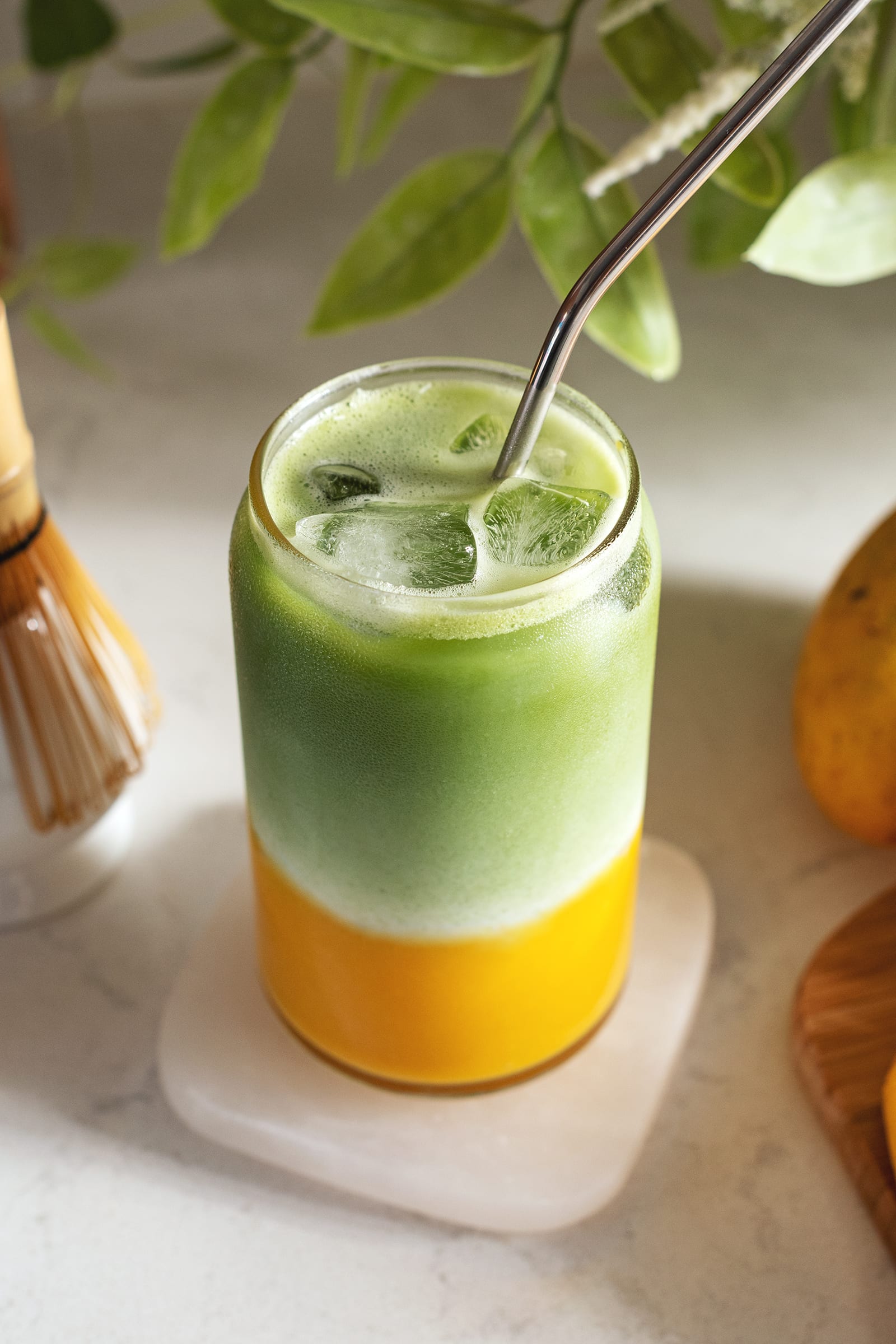 A glass of iced mango matcha latte.