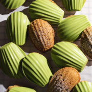 Matcha madeleines on parchment paper, some plain and some with a matcha chocolate shell.