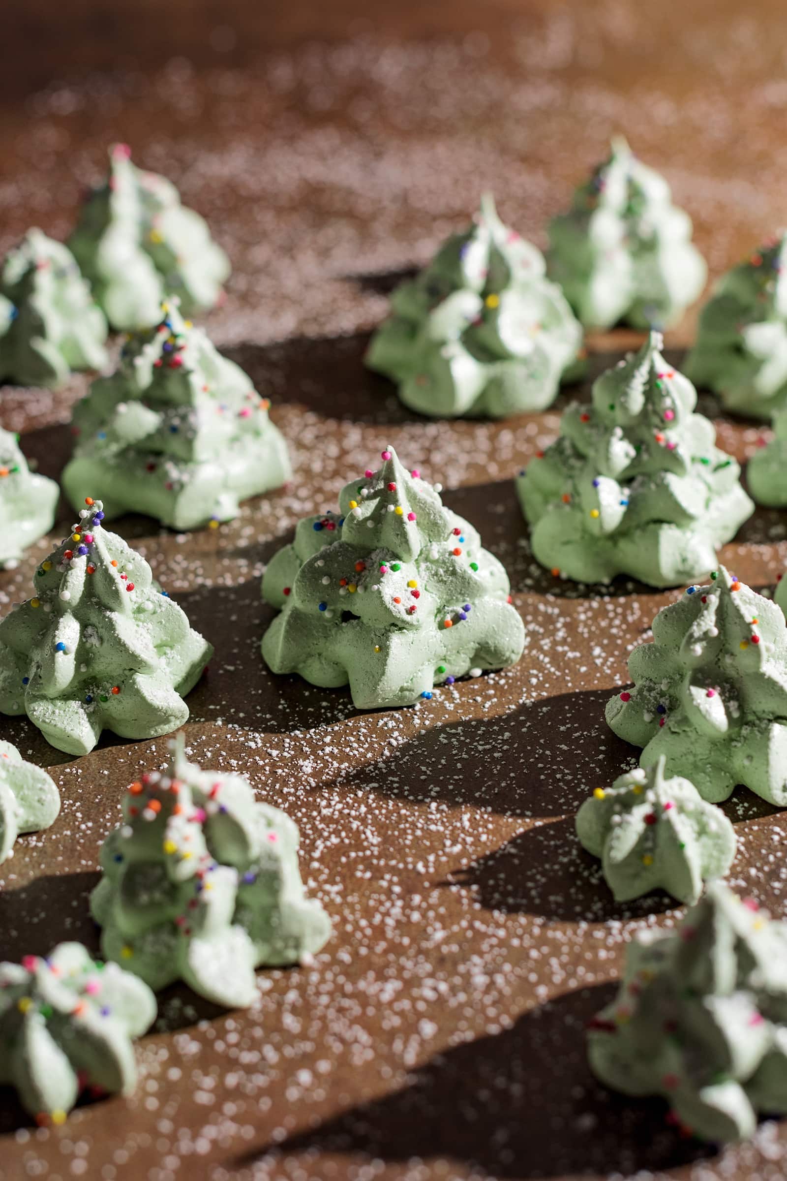 Meringue christmas trees sprinkled in powdered sugar.