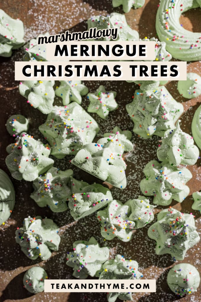 Green meringues shaped like christmas trees scattered on a wooden board.