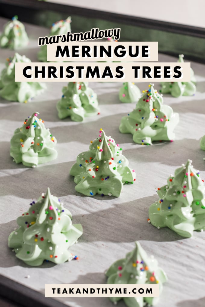 Meringue christmas trees covered in rainbow sprinkles on a baking sheet.