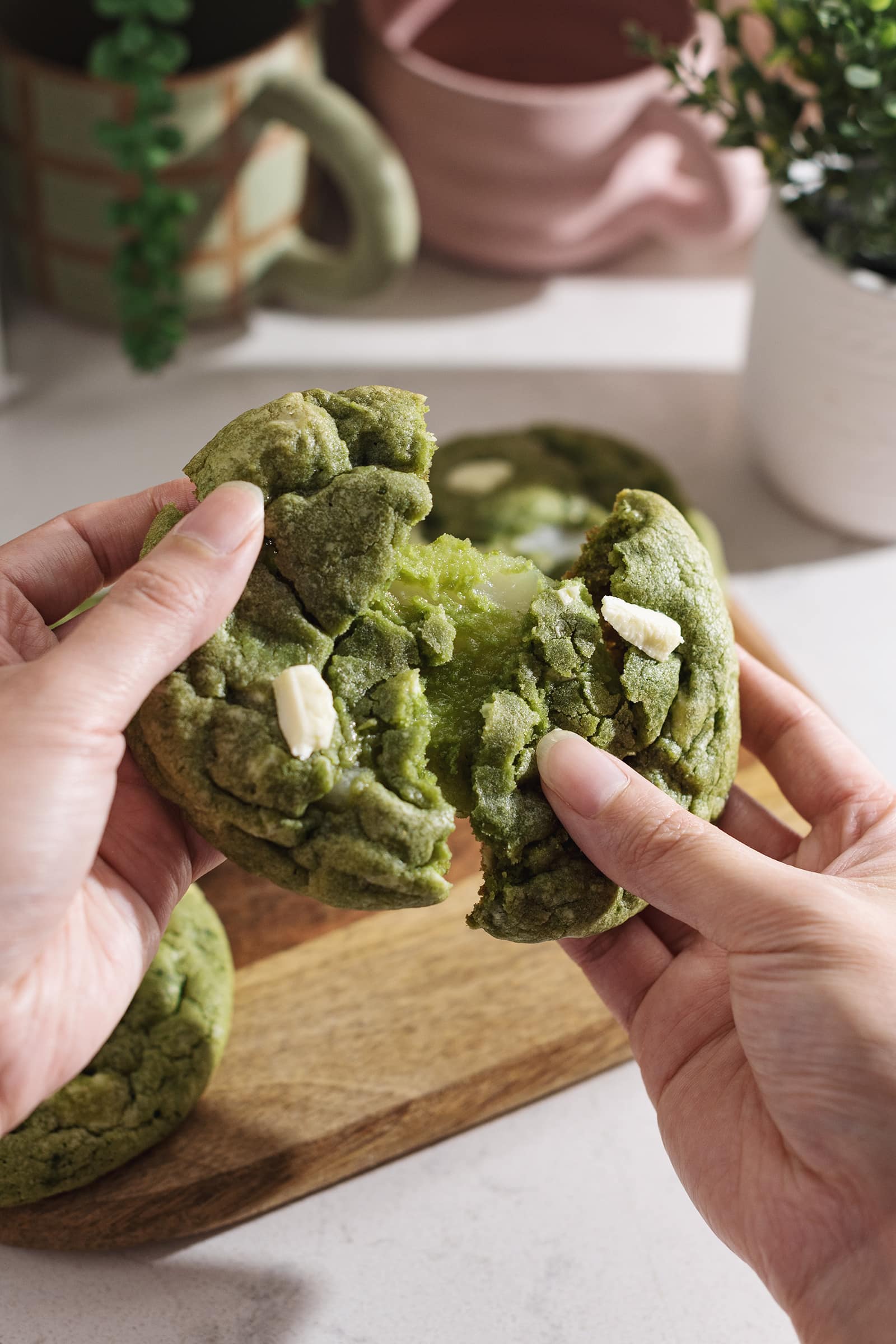 Pulling a matcha mochi cookie apart to show the stretchy mochi inside.