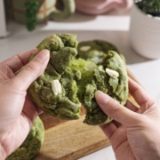 Pulling a matcha mochi cookie apart to show the stretchy mochi inside.
