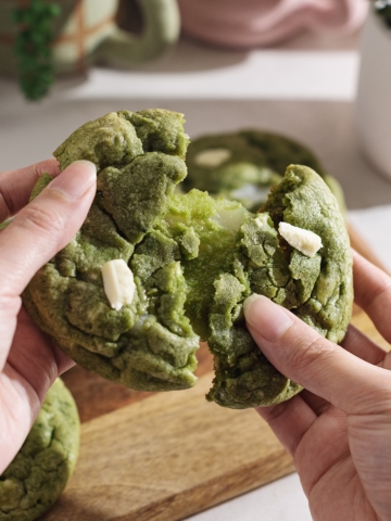 Pulling a matcha mochi cookie apart to show the stretchy mochi inside.