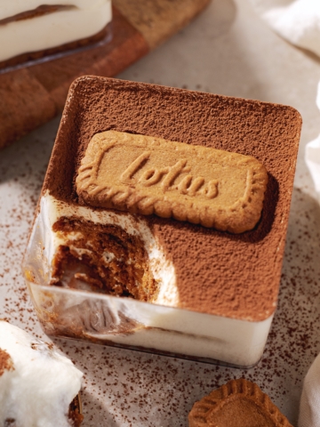 A square container of biscoff tiramisu with a spoonful scooped out of one corner.