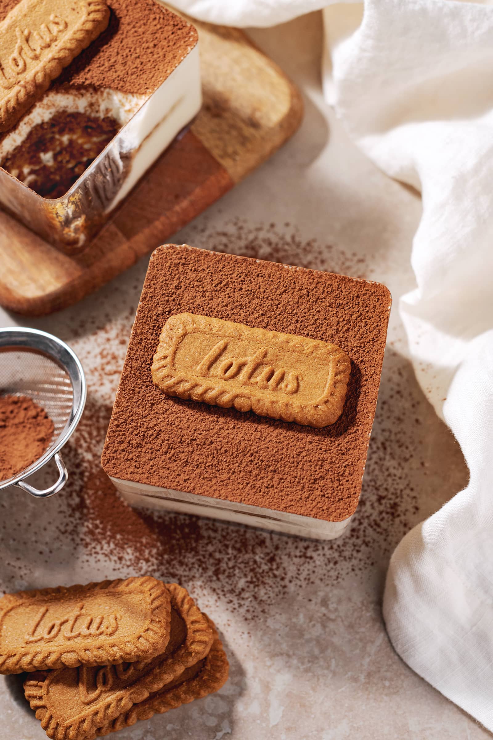 A box of biscoff tiramisu dusted with cocoa powder with a Lotus biscuit on top.