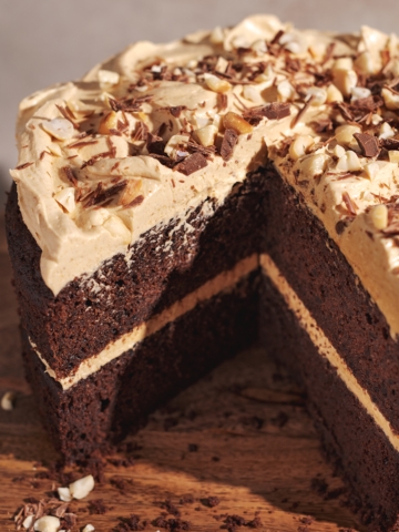 A triangle cut out of a chocolate cake with peanut butter frosting to show its layers.