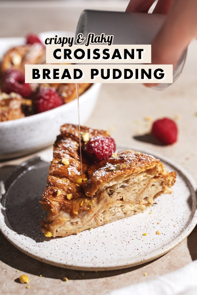 Hand pouring maple syrup onto a slice of croissant bread pudding.