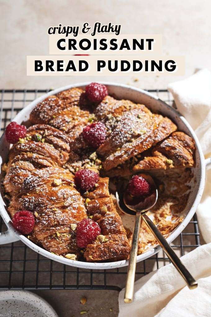 Croissant bread pudding in a baking dish with two spoons where a slice was cut out from it.