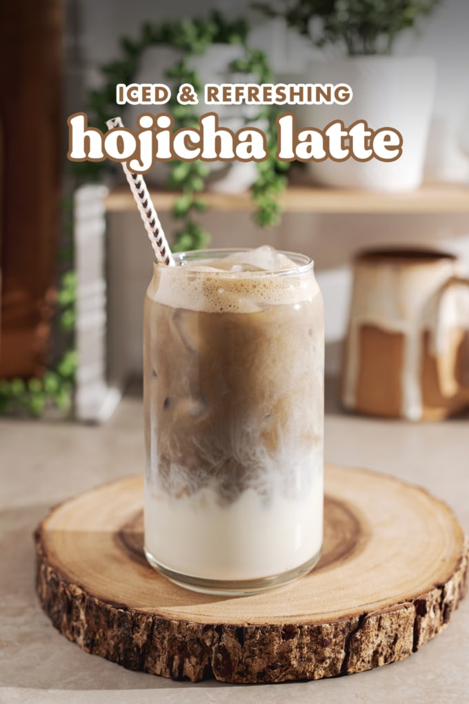 A glass filled with milk on the bottom and hojicha on top on a wood platter.