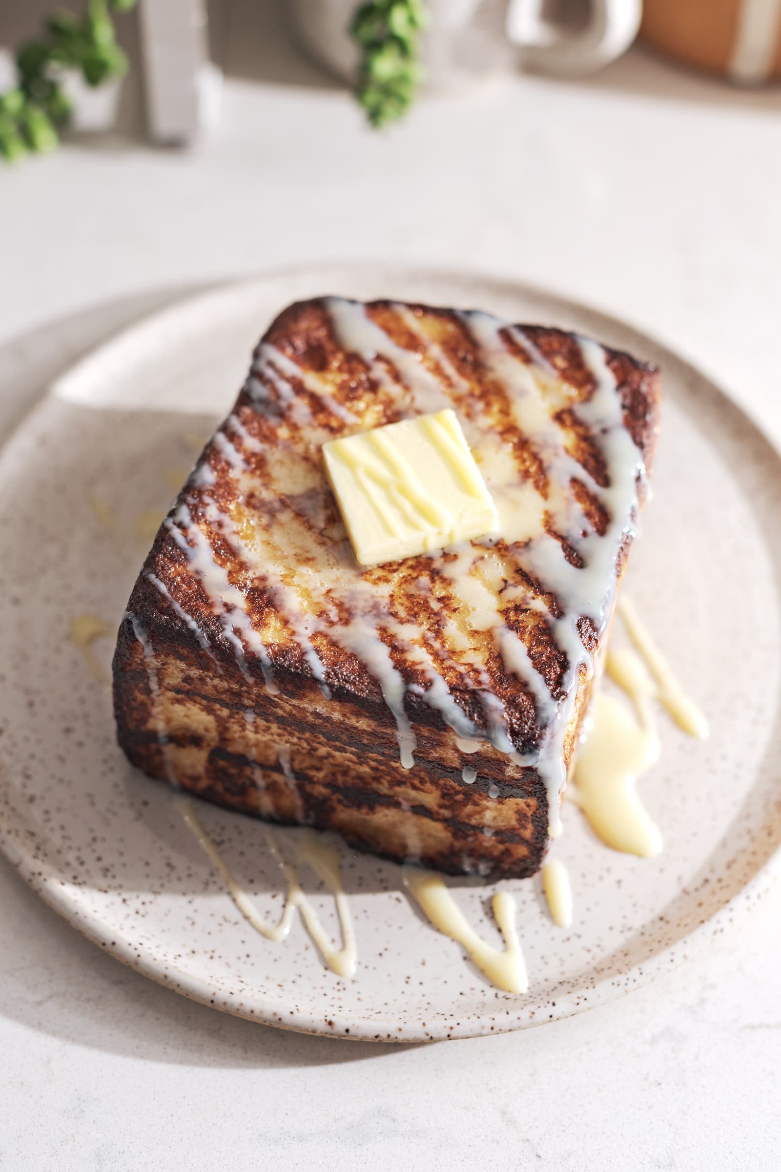 Hong Kong french toast on a plate with a square of butter on top and drizzled with condensed milk.