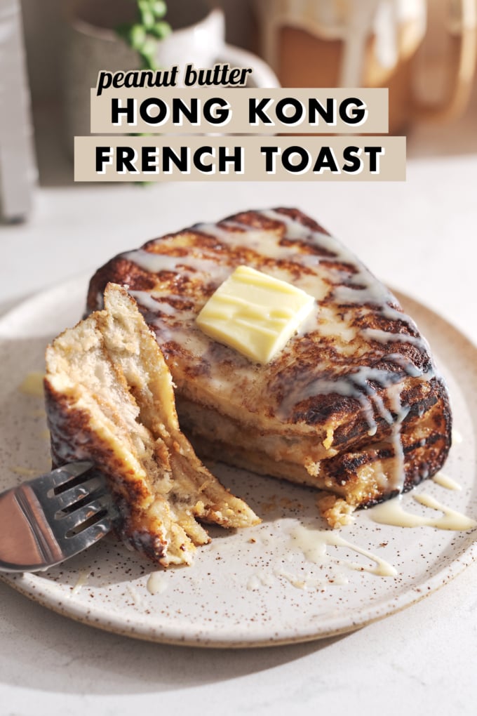 Fork with a piece of french toast resting on a plate next to the rest of the toast.