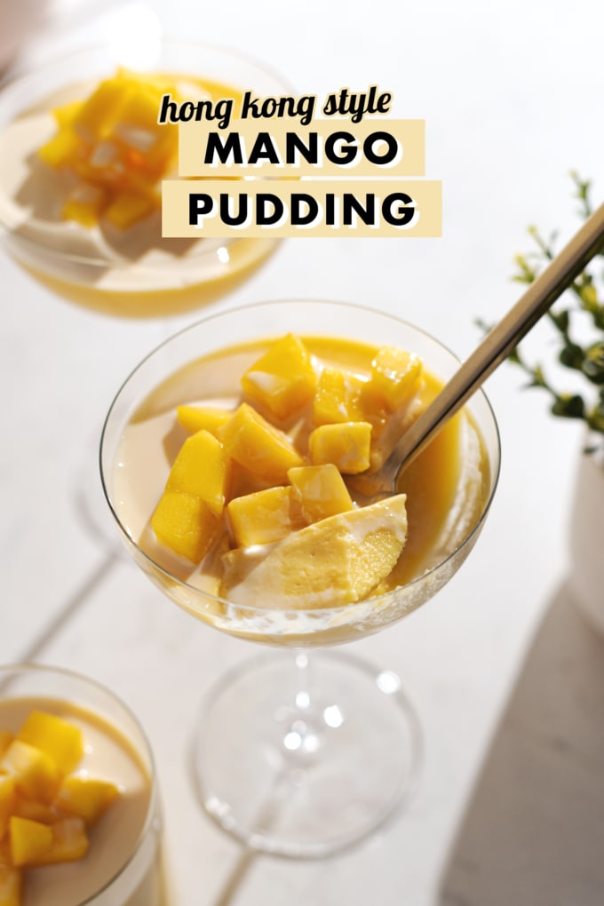 A spoonful of mango pudding resting in the glass with mango chunks on top.