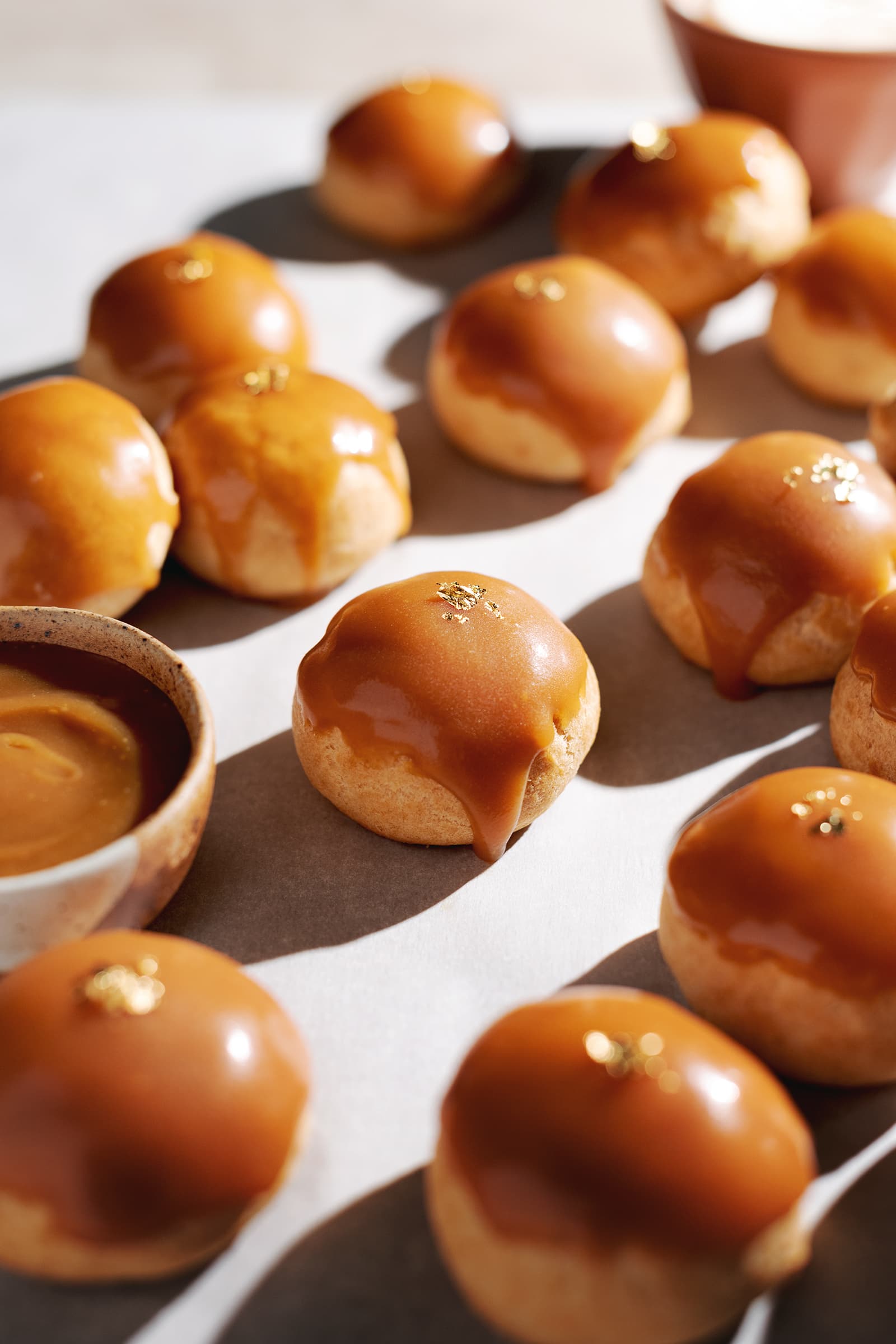 Profiterole with a caramel drip down the side surrounded by more cream puffs.