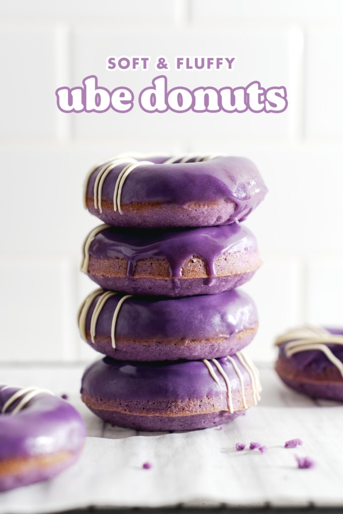 Four ube donuts stacked on top of each other with glaze dripping down the front.