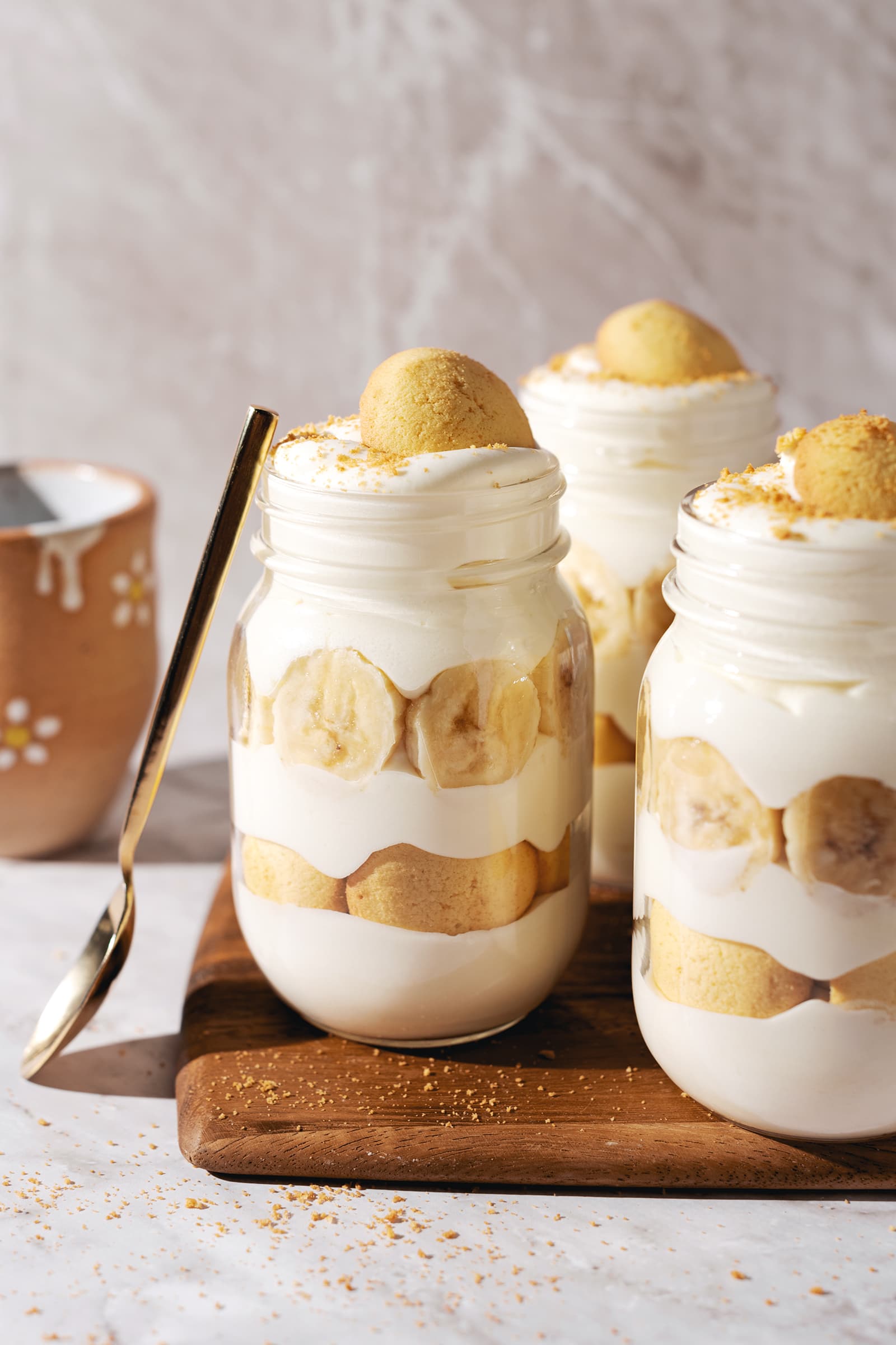 Three banana pudding jars with a spoon resting on the side.