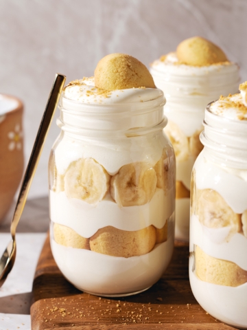 Three banana pudding jars with a spoon resting on the side.