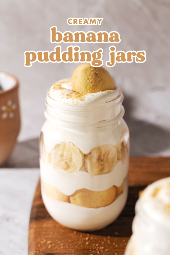 A jar of layered banana pudding on wooden board.