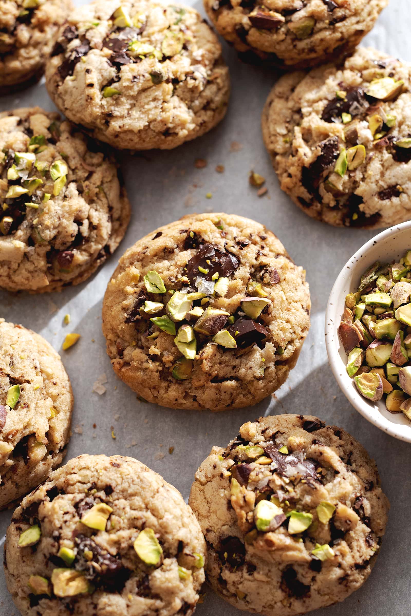 Cookies sprinkled with pistachios on parchment paper.