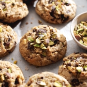 Pistachio chocolate chip cookie surrounded by many other cookies.