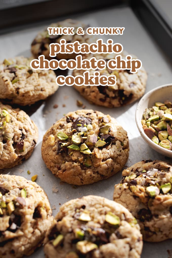 Pistachio chocolate chip cookie surrounded by many other cookies on a baking tray.