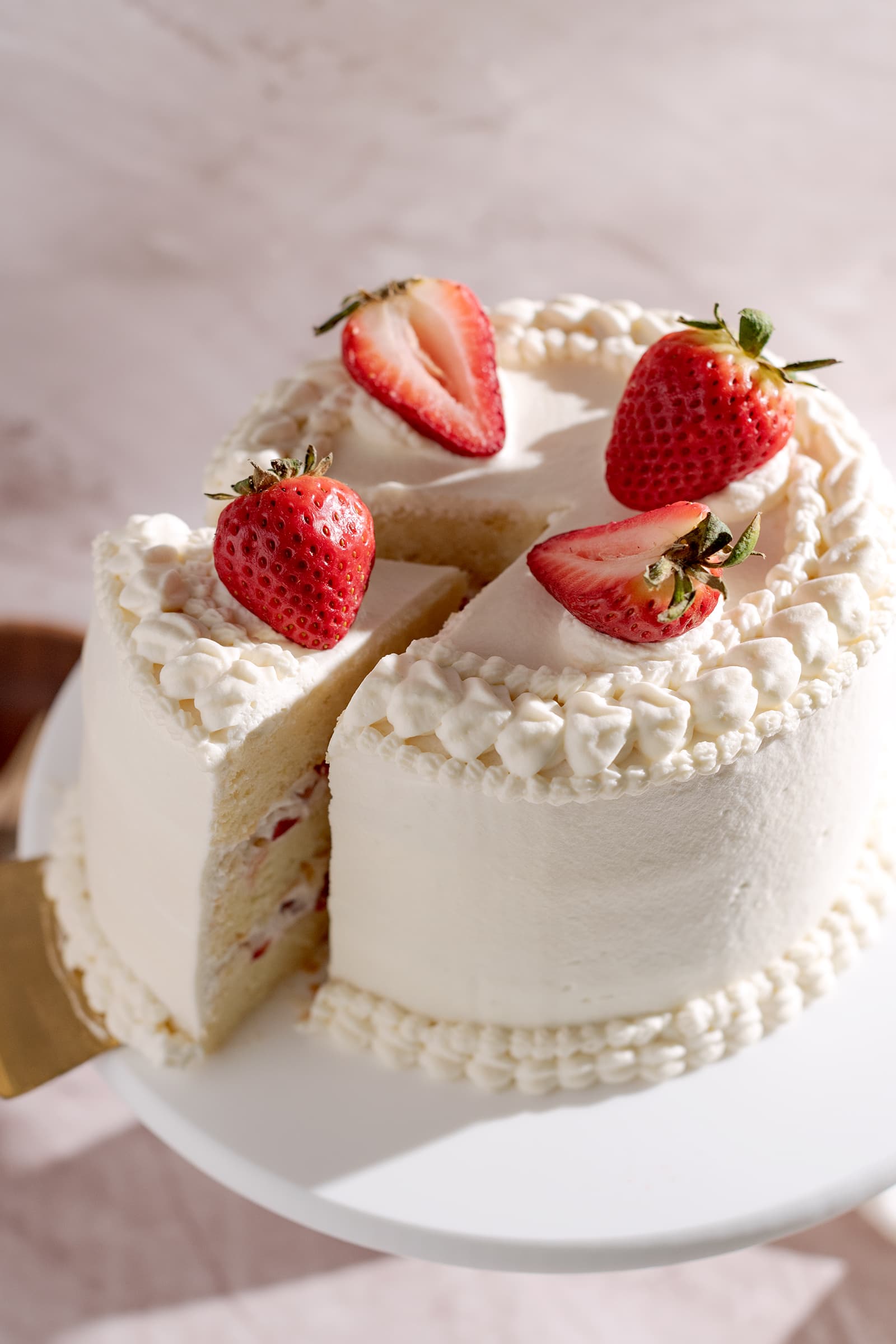 Strawberry chiffon cake with a slice cut out of it.